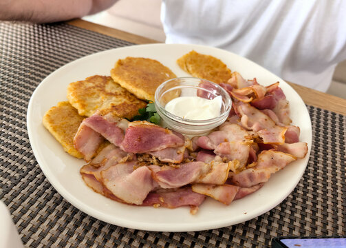 Traditional potato pancakes with bacon and sour cream top view