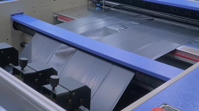 Automatic plastic bag making machine - production of black bags at packaging exhibition, factory: close up. Concept of industry, manufacturing, recycling, and technology equipment