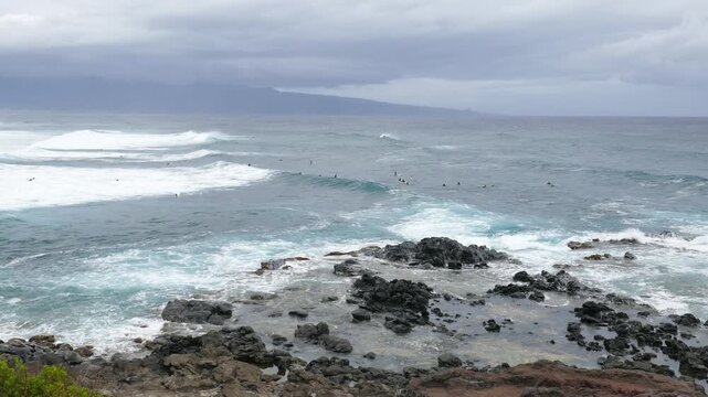 View from Ho'okipa Lookout at people surfing the waves of Hookipa Beach on the north shores of Maui, Hawaii.