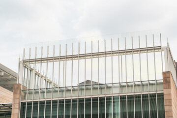 Modern architectural detail of a glass and stone building, showcasing a striking combination of reflective glass surfaces and textured stone elements © Juli