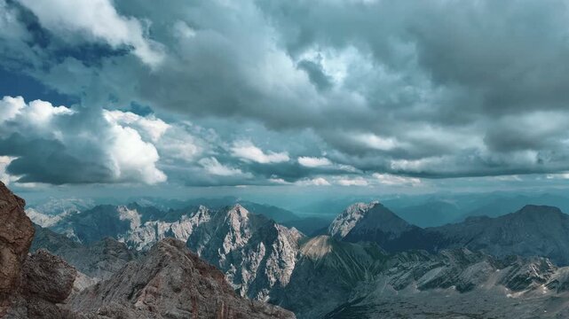 Breathtaking timelapse of fast moving clouds casting shadows over the majestic peaks of the German Alps, viewed from the Zugspitze summit