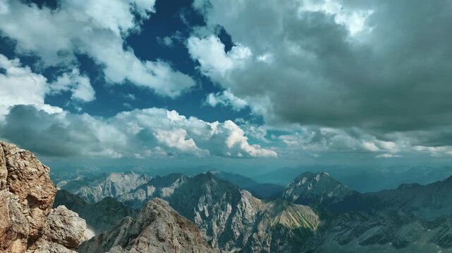 Stunning timelapse panorama capturing clouds rapidly flowing over the rugged peaks of the Alps, as seen from Zugspitze, Germany's highest mountain