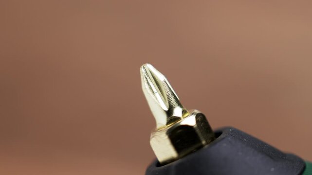 Metallic crosshead screwdriver bit attached to an electric cordless power tool chuck. Concept of DIY home renovation