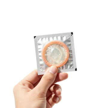 Hand holding condom wrapper against white background