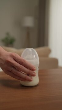 Close Up of a Baby Milk Bottle on a Wooden Table in a Cozy Living Room