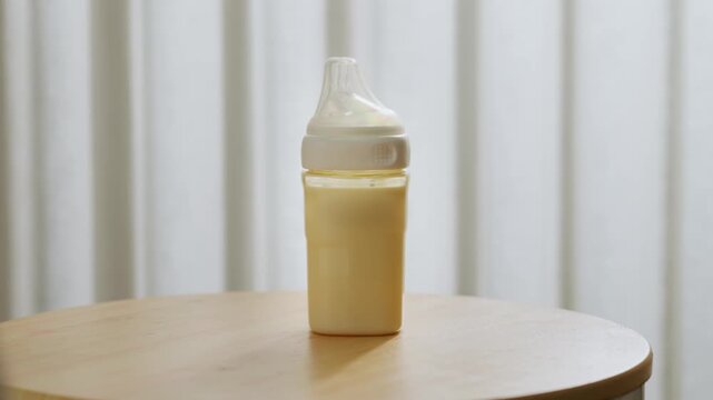 Fresh Pumped Breast Milk in a Baby Storage Bottle on a Round Table