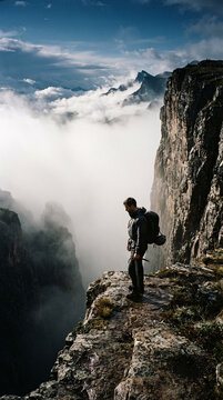 Climber Standing on Mountain Edge Above Foggy Valley