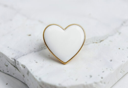 Blank white heart enamel pin on marble background, ai generated. Elegant heart-shaped badge with thin gold outline mockup. Minimal lapel design for custom branding, logo, merchandise concept.