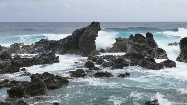 View from Ho'okipa Lookout of black volcanic rocks and waves of Hookipa Beach on the north shores of Maui, Hawaii.
