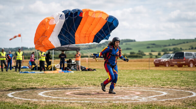 Female Skydiver Landing with Parachute on Target at Drop Zone During Extreme Sport Competition. Concept of parachuting, skydiving, parachutist, dropzone, airfield, accuracy landing, parachute jump.