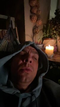 close low-angle view of adult male wearing hooded sweatshirt reclining indoors while eyes open and mouth slightly parted, indicating subtle transition from drowsy