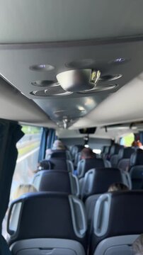 low upward view along interior aisle focusing on metallic dome reading light and circular air vents recessed into matte grey ceiling panel