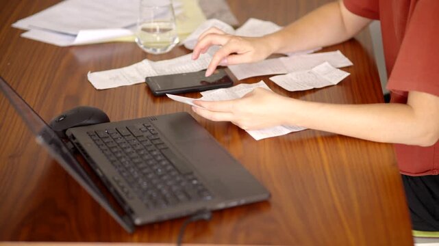 Checking Paper Receipts Bills Invoices With Laptop Smartphone. Managing Budget And Expenses 