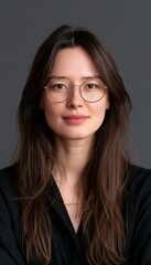 Fototapeta premium Confident young woman with glasses and long hair against charcoal background