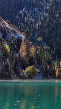First snow falling on autumn forest by emerald Issyk's lake, Kazakhstan