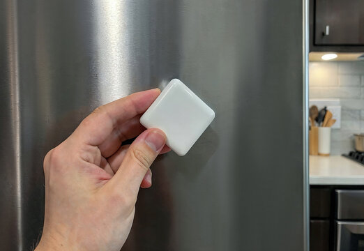 Blank rhombus souvenir magnet held by hand on refrigerator, ai generated. Clean customizable fridge magnet mockup with empty surface for logo, travel souvenir, photo, artwork, text or branding design.
