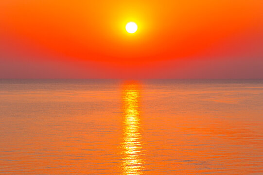 sunrise at the black sea. sun above horizon. reflection on the calm water. nature background in warm orange light