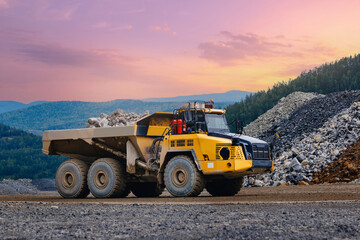Yellow articulated dump truck full of ore at quarry with sunset sky for industrial background and heavy equipment © Parilov