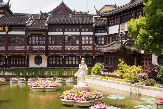 Yu Garden Shanghai features classical Ming style buildings, curved tile roofs, decorative lattice windows, flower rings, lotus forms and white sculpture beside calm garden water in layered courtyards