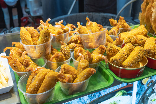 Deep-fried crispy prawns and seafood rolls with sesame seeds served in cups at a street food market stall. buying street food from asian market is fun street food