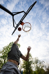 Man shooting basketball performing layup against blue sky © Zoran Jesic