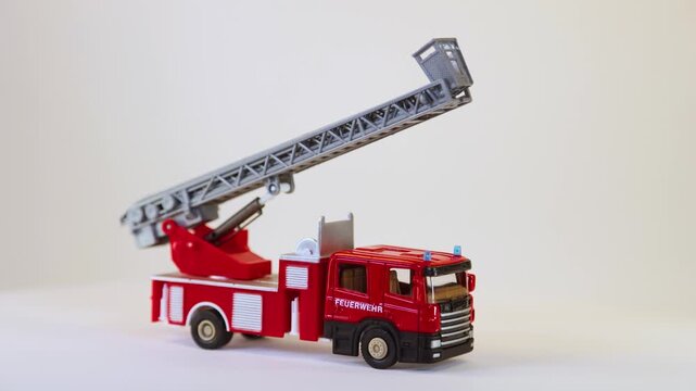 Toy fire truck with extending ladder rotating on white background