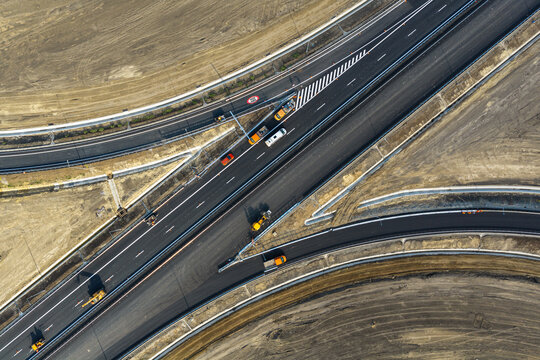 Aerial top down view of highway interchange construction site on Autostrada A7 near Bacau, featuring asphalt paving machinery, ramps, markings and transport concept. Moldova Highway in Romania