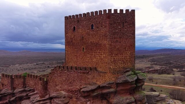 Zafra Castle medieval stone keep perched on rocky outcrop in Guadalajara province, Spain, with vast Castilian plains and dramatic cloudy sky stretching to the horizon