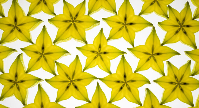 Bright yellow star fruit slices pattern on white background perfect for tropical summer food concepts and fresh healthy nutrition designs