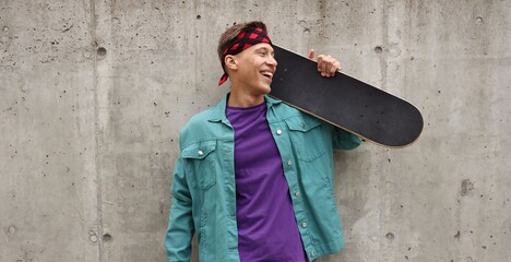 Happy man with skateboard near grey wall outdoors © New Africa