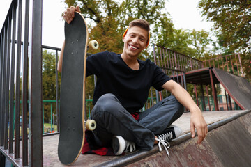 Stylish man with skateboard on ramp in skate park © New Africa