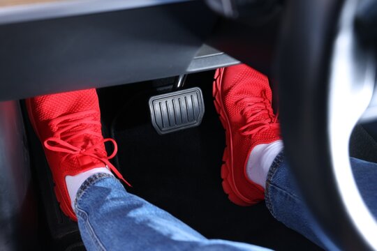 Woman pushing accelerator pedal in car, closeup on foot