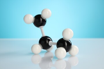 Chemical model of molecule on white table against light blue background, closeup