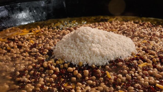 Uzbek oshpaz pours freshly washed rice into a large kazan while preparing traditional wedding plov. Authentic Central Asian cooking. Tourism, travel, culinary content, documentaries and cultural