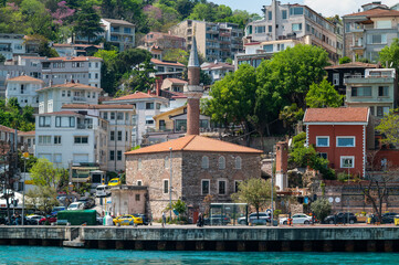 Sunlit stone mosque stands beside turquoise water © Raul