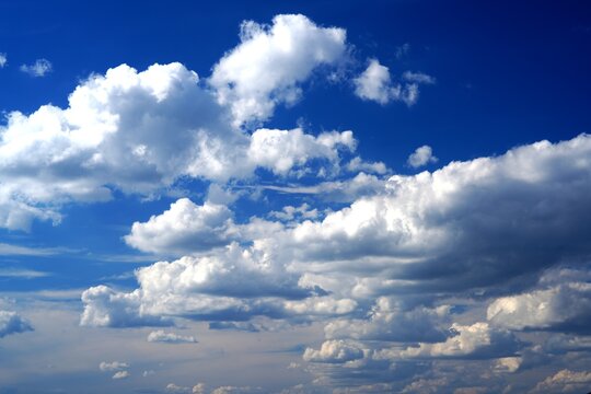 Vibrant deep blue sky filled with picturesque fluffy white cumulus and cirrus clouds, perfect for nature background, weather concepts, and design projects.
