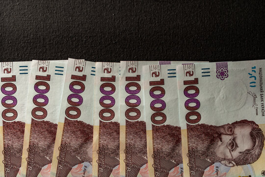 Row of Ukrainian 1000 hryvnia bills featuring Volodymyr Vernadsky on dark surface, closeup. Excellent for business, finance, banking, and economic concepts related to Ukraine