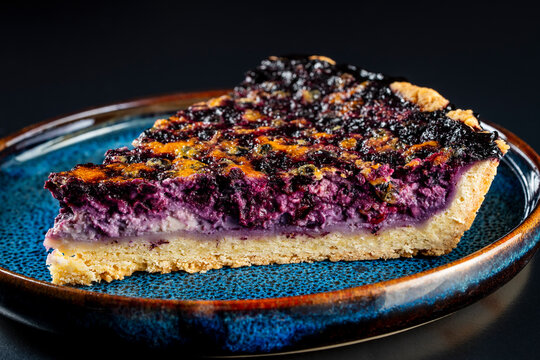 Slice of homemade blueberry pie. Delicious slice of berry tart with rich purple filling served on beautiful textured blue plate. Perfect for bakeries, dessert menus, and culinary blogging