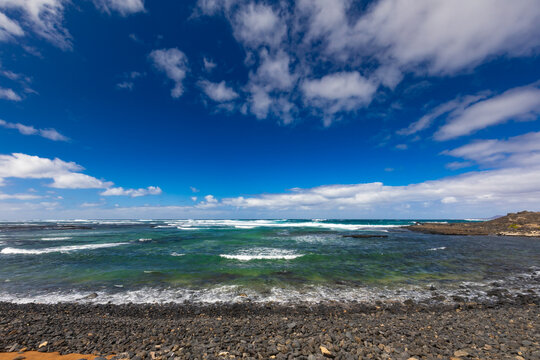 Panoramic view of a volcanic beach and the turquoise Atlantic Ocean under a blue sky on Fuerteventura (Canary Islands) &ndash; a background or wallpaper for your project