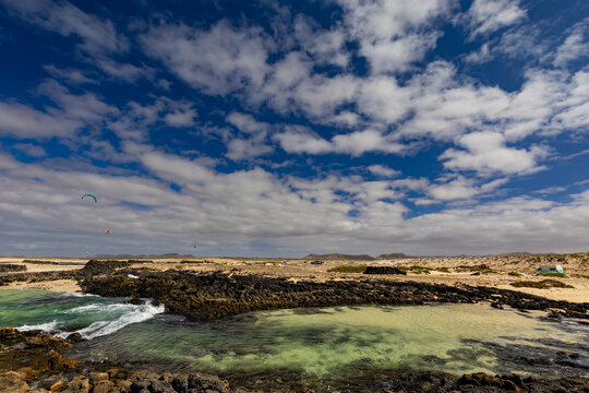 Panoramic view of a volcanic beach and the turquoise Atlantic Ocean under a blue sky on Fuerteventura (Canary Islands) &ndash; a background or wallpaper for your project