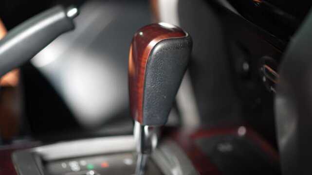 Car automatic transmission gear shift knob featuring a dark wood grain inlay and black textured leather upholstery, matching the Toyota Land Cruiser interior design.