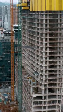 Aerial view of high rise building under construction with tower cranes in modern cityscape. Urban construction, real estate development, city expansion, housing demand, investment