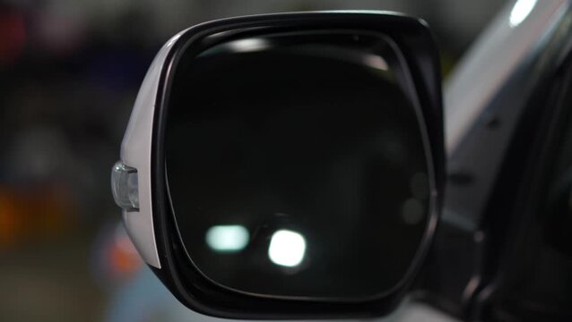 Car side view mirror with a white outer housing, an integrated clear turn signal indicator lens, and an adjustable reflective glass surface.