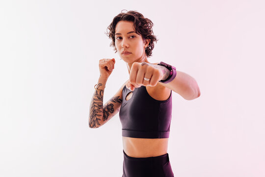 Slim woman practicing punches in a studio, showing her fist in camera