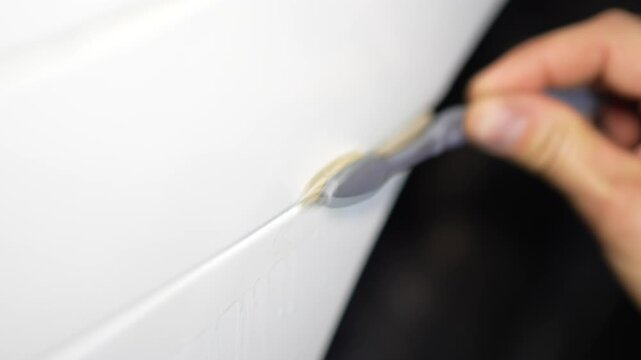 Detailer using a brush to clean dirt from the car fender gap.