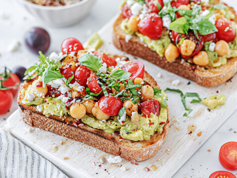 avocado toast with diced cherry tomatoes, chickpeas, crumbled feta cheese, fresh basil and abalsamic glaze 