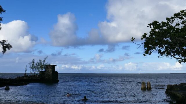 View from Coconut Island (Moku Ola) in Hilo Bay, Hilo, Hawaii. on the big island. Shot on a spring day April, 2023. Small stone tower platform for swimmers for jumping or diving into the water.