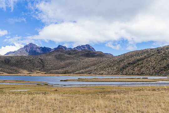 A scenic view of the high-altitude Limpiopungo lagoon (lake) with the dramatic peaks of the Rumi&ntilde;ahui volcano under a blue sky in the Ecuadorian Andes  within Cotopaxi National Park