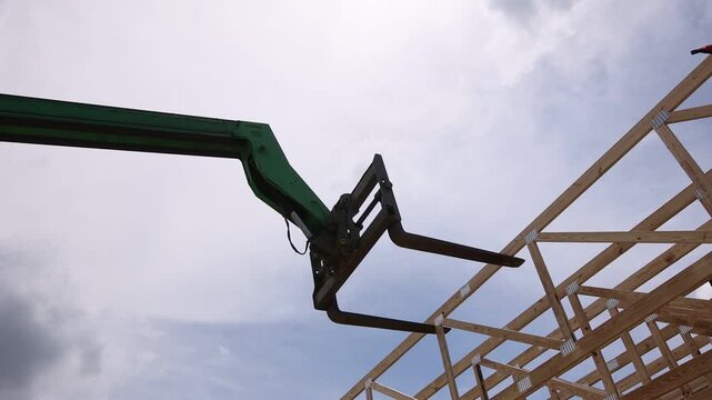 Crane lifts wooden beams into place at construction site framework for residential construction