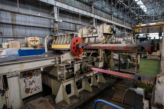 Industrial machinery in large factory with rusted metal and red accents under high ceiling